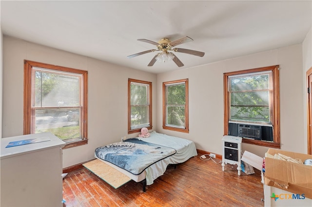 bedroom with cooling unit, ceiling fan, and light hardwood / wood-style flooring