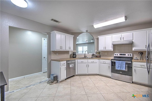 kitchen featuring under cabinet range hood, a sink, visible vents, appliances with stainless steel finishes, and backsplash