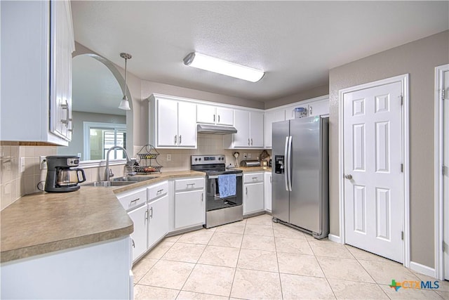 kitchen featuring tasteful backsplash, appliances with stainless steel finishes, light tile patterned flooring, a sink, and under cabinet range hood