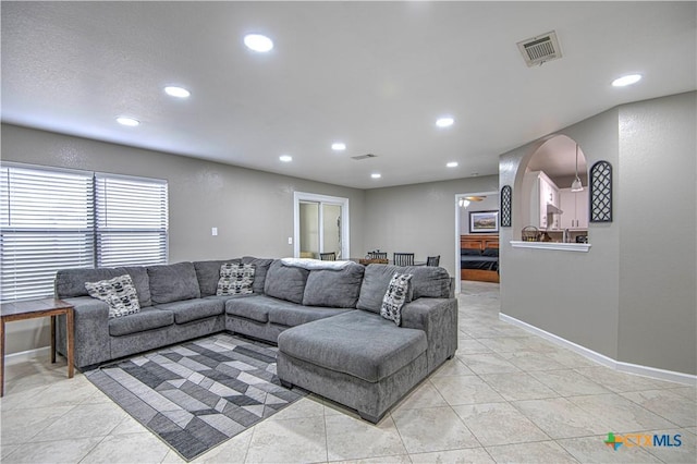 living area featuring arched walkways, visible vents, baseboards, and recessed lighting