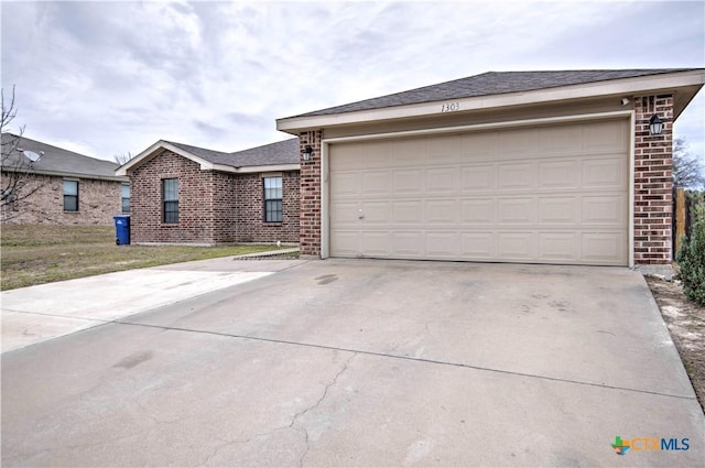 single story home with driveway, a garage, a shingled roof, a front lawn, and brick siding