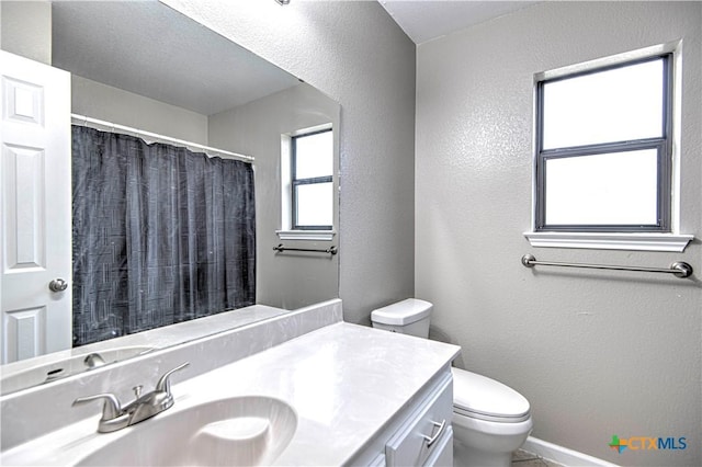 full bath featuring curtained shower, a textured wall, vanity, and toilet