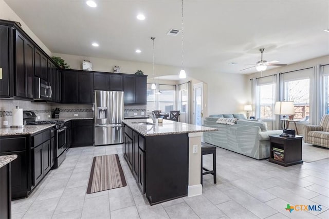 702 Old Settlers Dr, San Marcos, TX 78666 - kitchen with stainless steel appliances, a ceiling fan, a sink, light stone counters, and open floor plan