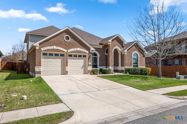 702 Old Settlers Dr, San Marcos, TX 78666 - view of front facade featuring fence, an attached garage, driveway, a front yard, and brick siding