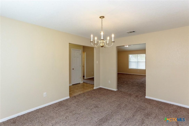 carpeted spare room featuring a notable chandelier