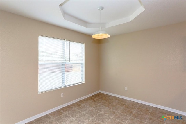 unfurnished room featuring light tile patterned flooring, a raised ceiling, and a wealth of natural light