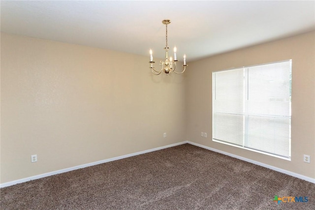 spare room featuring carpet and a notable chandelier