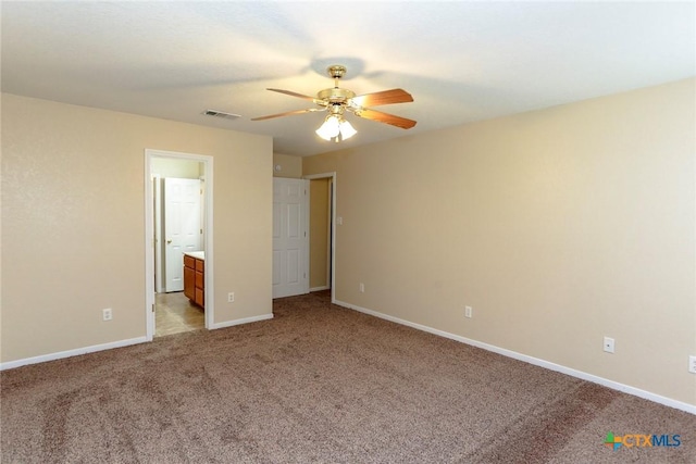 unfurnished bedroom with light colored carpet, ensuite bath, and ceiling fan