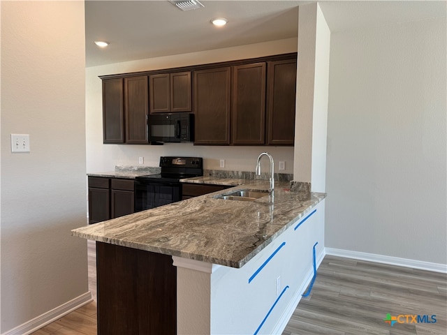 kitchen featuring dark brown cabinetry, sink, black appliances, light stone counters, and kitchen peninsula