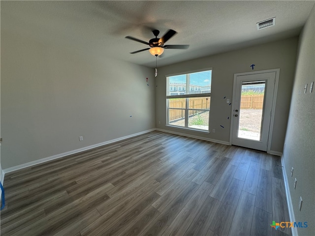 empty room featuring dark hardwood / wood-style flooring, a textured ceiling, and ceiling fan