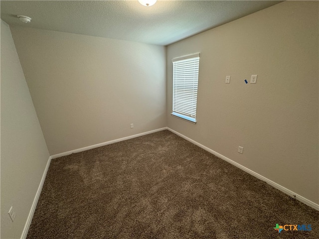 empty room with a textured ceiling and dark carpet