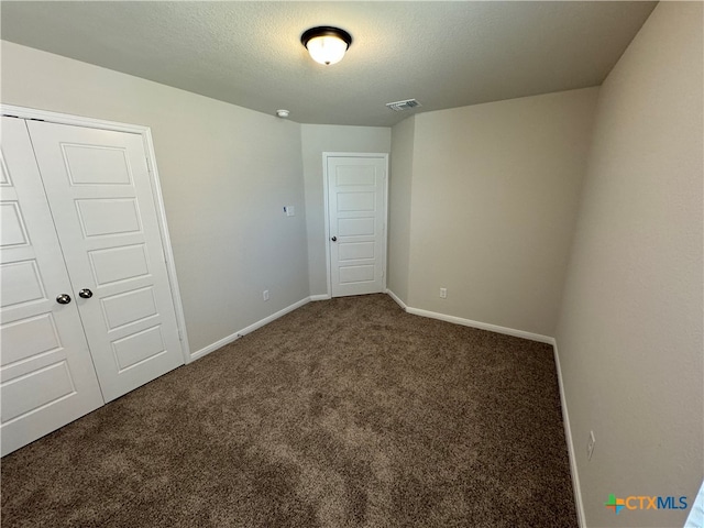 spare room with dark colored carpet and a textured ceiling