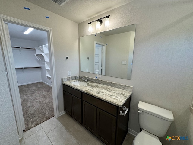 bathroom featuring tile patterned flooring, vanity, a textured ceiling, and toilet