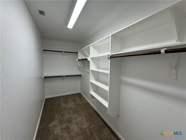 walk in closet featuring dark carpet