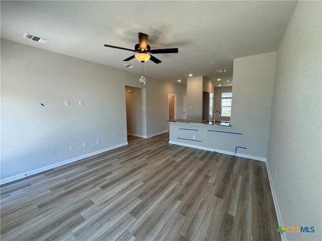 unfurnished living room with ceiling fan, a textured ceiling, sink, and light hardwood / wood-style flooring