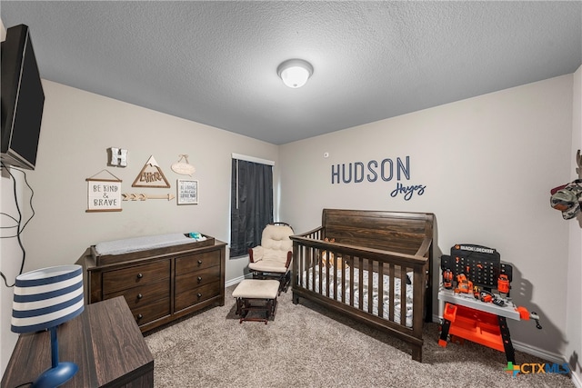 bedroom featuring a textured ceiling, light colored carpet, and a crib