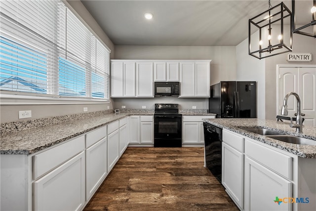 kitchen with black appliances, white cabinets, sink, hanging light fixtures, and dark hardwood / wood-style floors