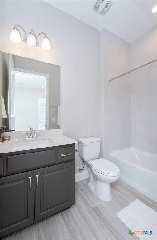 full bathroom featuring tiled shower / bath combo, vanity, and toilet