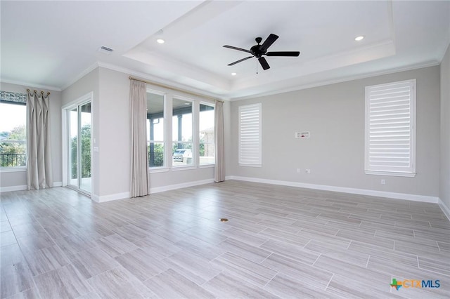 empty room with crown molding, ceiling fan, a raised ceiling, and light hardwood / wood-style flooring