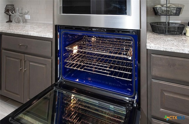 interior details with decorative backsplash, dark brown cabinets, and oven