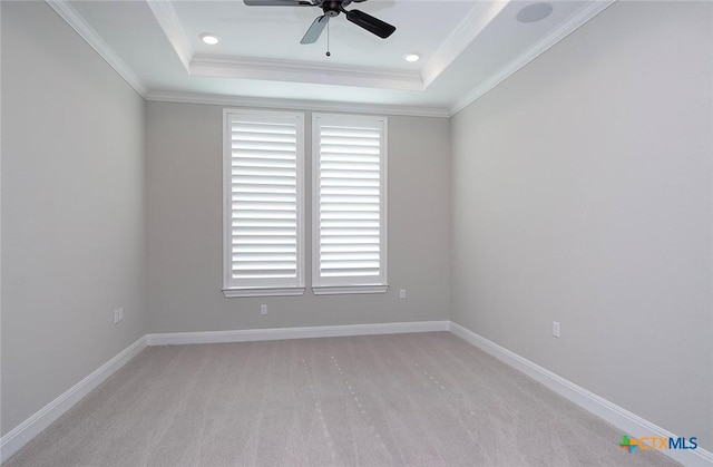 carpeted spare room with crown molding, a tray ceiling, and ceiling fan