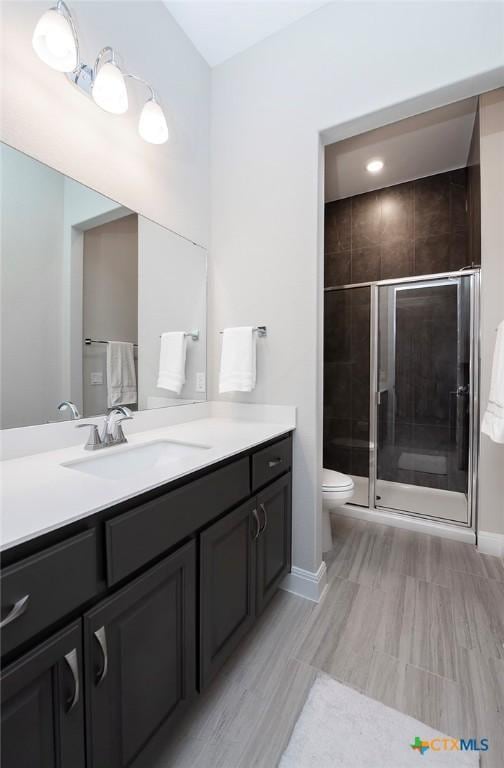 bathroom with vanity, an enclosed shower, and toilet