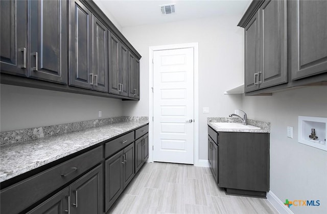 clothes washing area with cabinets, hookup for a washing machine, and sink