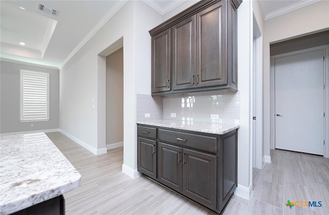 kitchen with light stone counters, decorative backsplash, dark brown cabinets, and crown molding