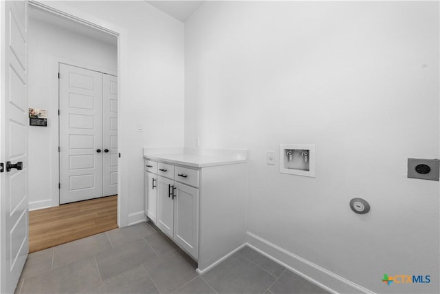 laundry room with cabinet space, light tile patterned floors, baseboards, hookup for a washing machine, and electric dryer hookup