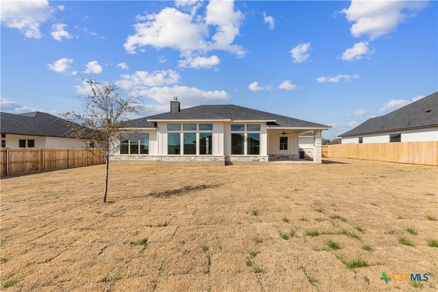 rear view of property featuring a patio area, a fenced backyard, and a chimney