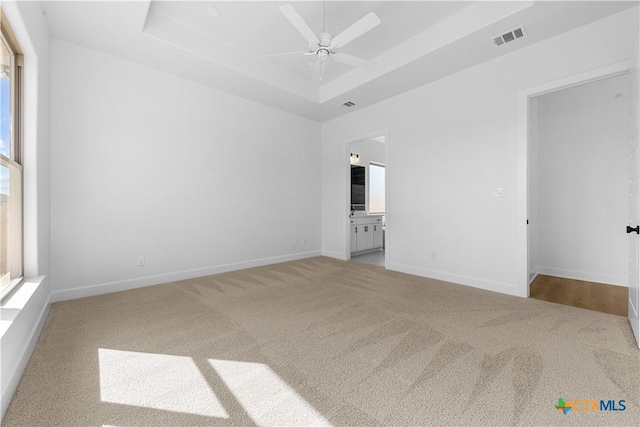 unfurnished room featuring visible vents, baseboards, ceiling fan, a tray ceiling, and carpet flooring