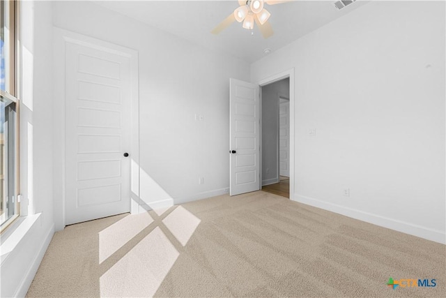 unfurnished bedroom with light carpet, ceiling fan, visible vents, and baseboards