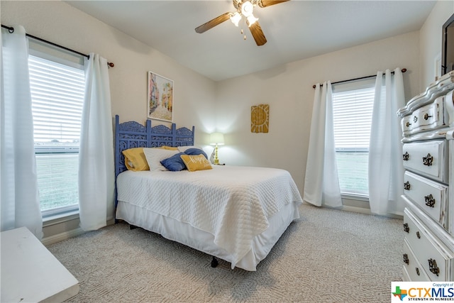 carpeted bedroom featuring ceiling fan and multiple windows