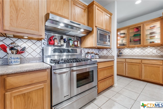 kitchen with ventilation hood, decorative backsplash, light tile patterned flooring, and stainless steel appliances