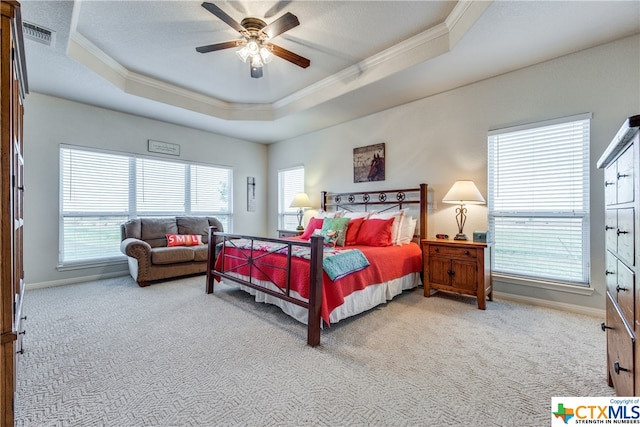 carpeted bedroom with crown molding, ceiling fan, and a raised ceiling