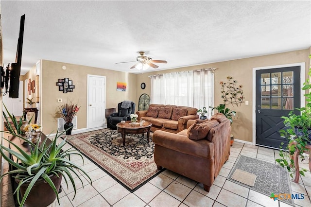 living room with ceiling fan, light tile patterned floors, and a textured ceiling