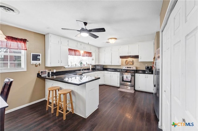 kitchen with a kitchen breakfast bar, dark hardwood / wood-style flooring, kitchen peninsula, white cabinets, and appliances with stainless steel finishes