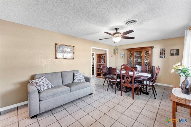 dining space with baseboards, a textured ceiling, a ceiling fan, light tile patterned flooring, and visible vents