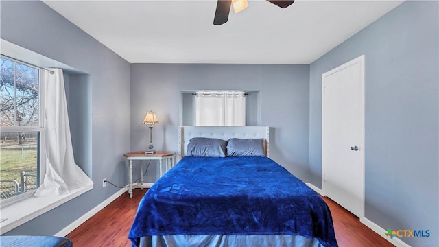bedroom featuring baseboards, multiple windows, ceiling fan, and wood finished floors