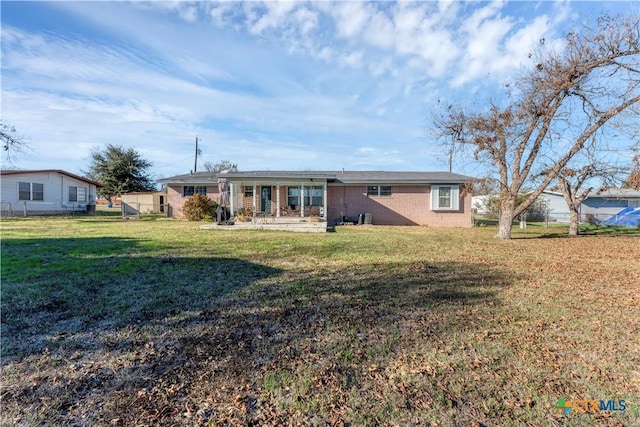 rear view of house featuring fence and a lawn