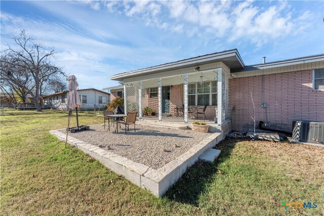 back of property with a yard, brick siding, and central air condition unit