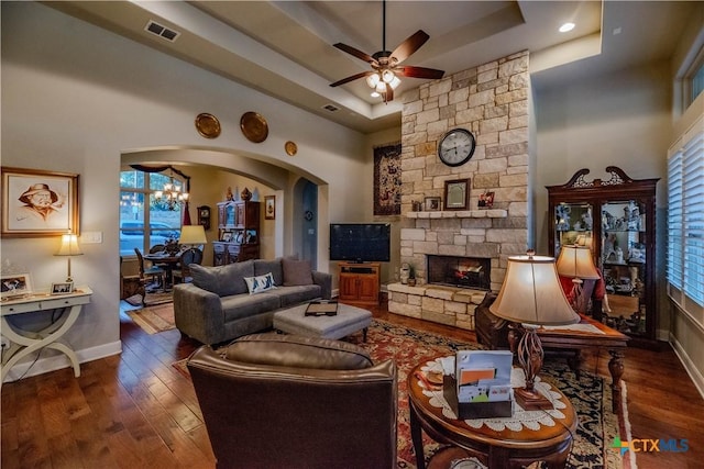 living area with a tray ceiling, wood-type flooring, visible vents, and a fireplace