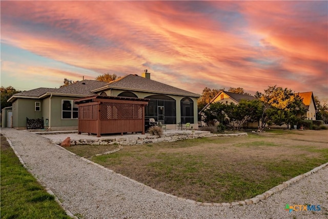 view of front of house with a sunroom, a chimney, a front lawn, and stucco siding