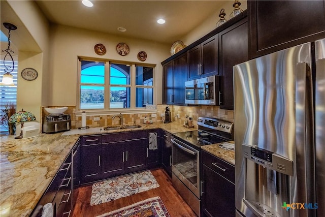 kitchen featuring stainless steel appliances, a sink, light stone counters, and tasteful backsplash