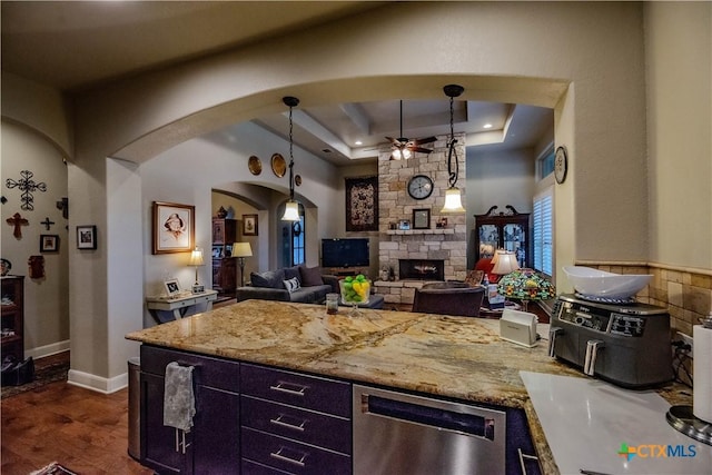 kitchen featuring arched walkways, a raised ceiling, dishwasher, dark wood-type flooring, and a fireplace