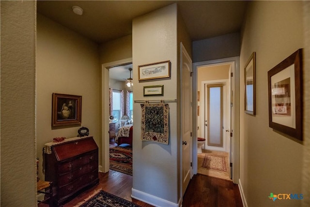 hall with baseboards and wood finished floors