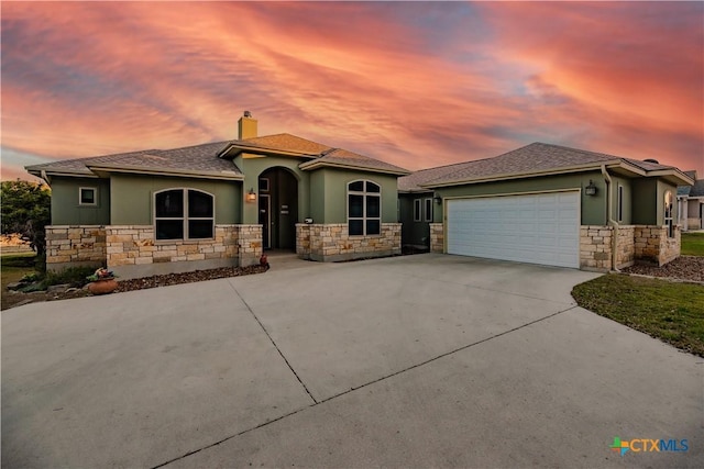 mediterranean / spanish-style home featuring stone siding, concrete driveway, an attached garage, and stucco siding