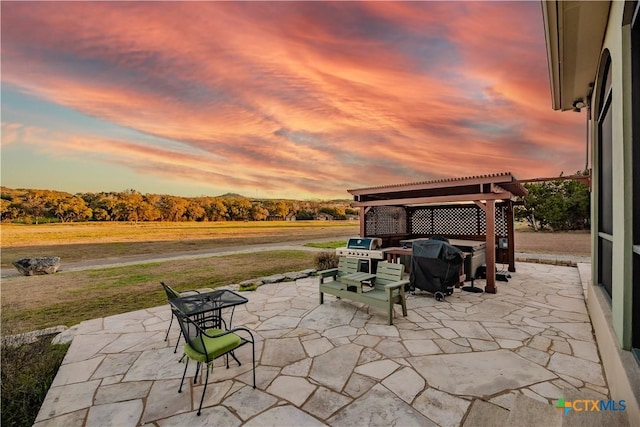 patio terrace at dusk featuring a lawn and a pergola