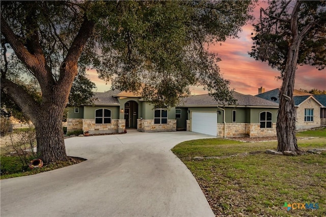 view of front of house featuring a garage, stone siding, a lawn, and stucco siding