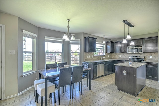 9505 Shimla Dr, Killeen, TX 76542 - kitchen featuring appliances with stainless steel finishes, backsplash, a kitchen island, light tile patterned flooring, and a textured ceiling